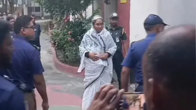 দীপু মনি দাঁড়িয়ে আছেন, তার পাশে পুলিশ সদস্যরা