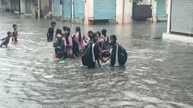 दिल्ली के दुर्गा विहार में गलियों में भरा पानी और उससे होकर घर जाते स्टूडेंट्स