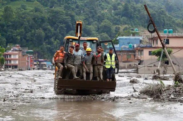 Homens em pé em trator em meio à lama