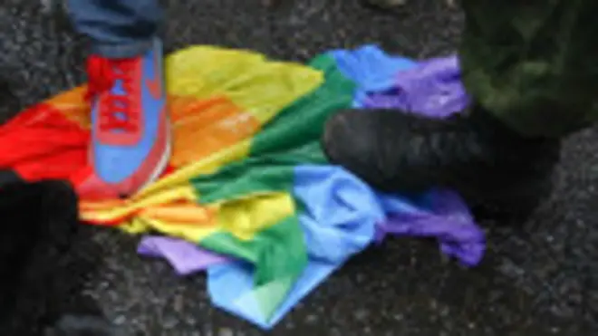 Manifestantes antigay pisan una bandera arcoíris