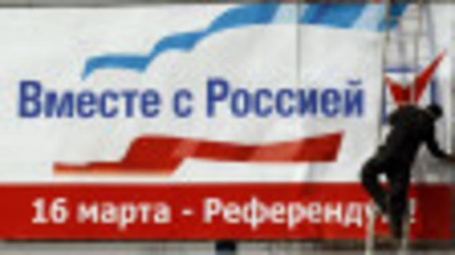 Рабочий вывешивает плакат (Симферополь, 12 марта 2014 г.)