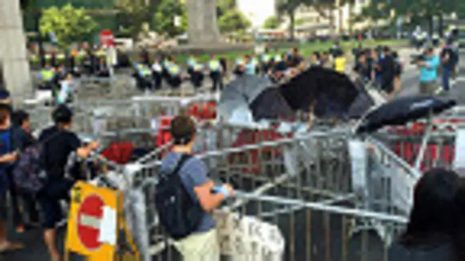 香港「佔領中環」行動參與者在幹諾道中中環段隔著剩餘路障與警察對峙  （BBC中文網圖片13/10/2014）