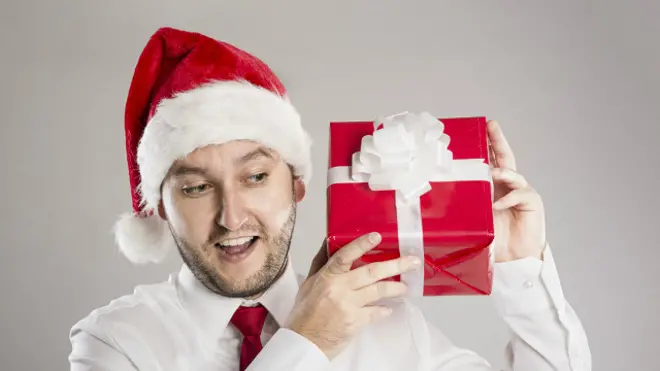 Un ejecutivo con sombrero de Papá Noel y una caja de regalos