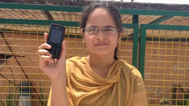 अपना मोबाइल दिखाती एक महिला