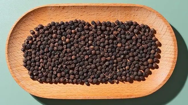 কাঠের একটি ট্রেতে কালো গোলমরিচ রাখা