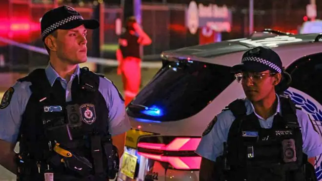 Two Australian police officers standing guard at the scene of a shooting at Bondi beach.