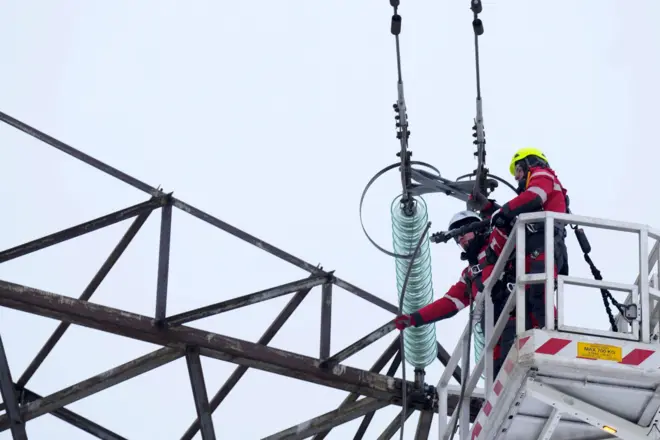 Рабочий перерезает провод