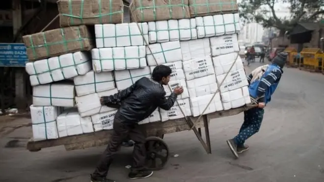 दिल्ली में सामान ले जा रहे मज़दूर