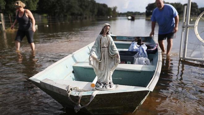 Leigh Babin y su esposo TJ Babin trasladan el barco una estatua de la Virgen María y otros objetos de su casa inundada en Sorrento, Luisiana, EE.UU.