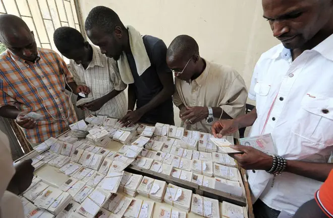 Des hommes s'affairant autour de lots de cartes d'identité