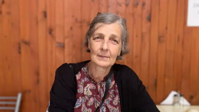 Mulher idosa com casaco preto e blusa estampada