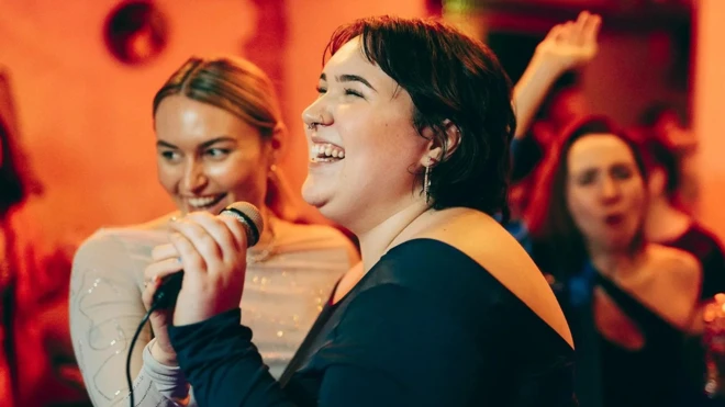 गाना गा रही महिलाओं का एक समूह है.