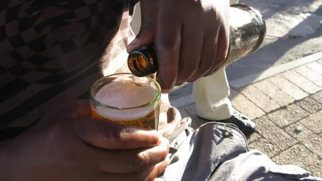 A man pouring a beer at a shebeen in South Africa