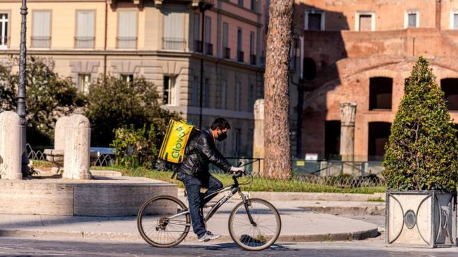 A food delivery man rides his bicycle in Rome