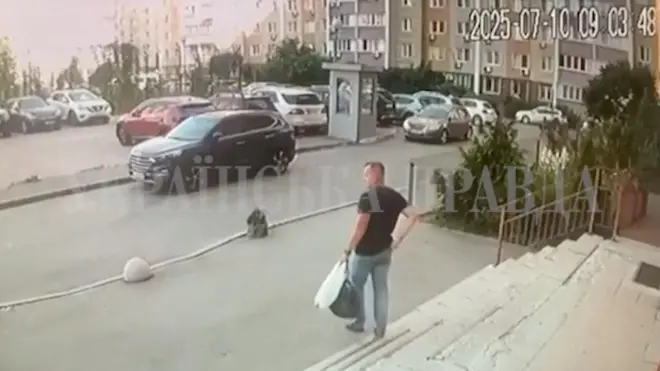 Umugabo wambaye ipantalo y'ikoboyi n'umupira wijimye w'amaboko magufi afite ishashi n'igikapu kijyamo ibintu binyuranye, abitwaye mu kuboko kumwe, arimo kugenda ava mu nyubako, yerekeza ahaparikwa imodoka, i Kyiv, muri Ukraine.