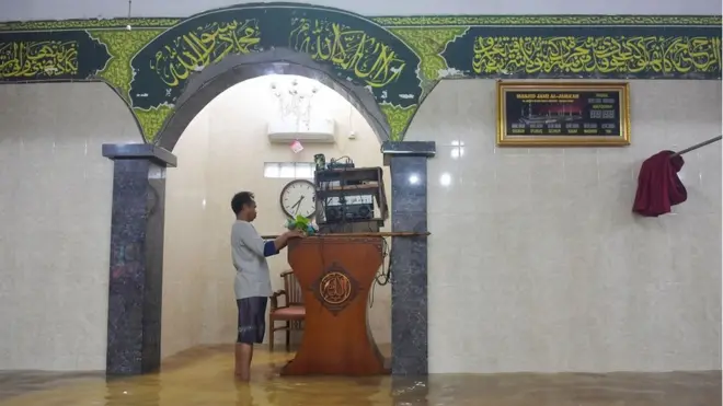 Warga meletakkan alat pengeras suara ke atas mimbar di Masjid Jami' Al-Jamaah yang terendam banjir di Jalan Anyer, Menteng, Jakarta, Minggu (23/2).