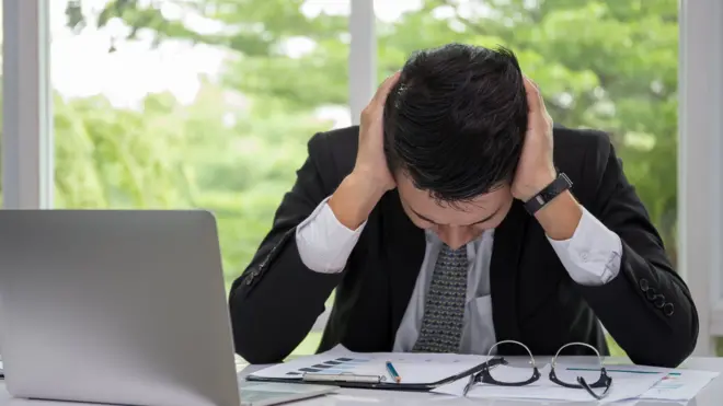 File photo: A stressed worker by his laptop