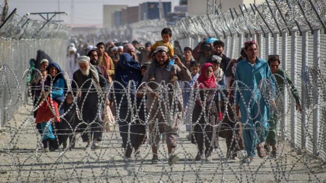 Afganos caminan entre las vallas en la frontera entre Afganistán y Pakistán, 24 de agosto 2021