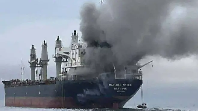 Sebuah kapal kargo milik Thailand terlihat sedang berada di tengah laut di Selat Hormuz dengan kondisi mengeluarkan asap tebal di bagian depannya.