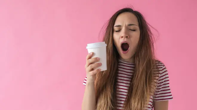 دختری لیوان بدست خمیازه می‌کشد