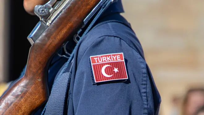 Silah tutan bir askerin omzunda Türk bayrağı gözüküyor