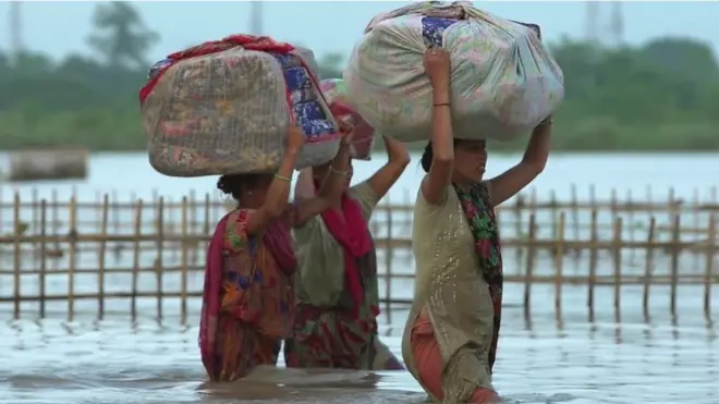 Mujeres cruzando un camino inundado