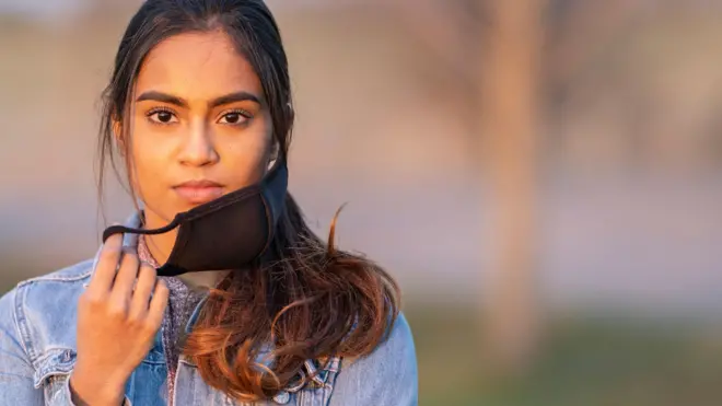 Portrait of an ethnic female standing outside wearing a protective face mask to avoid the transfer of germs during COVID-19