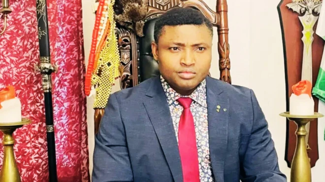 Simon Ekpa wear red tie wit suit, edey look straight.