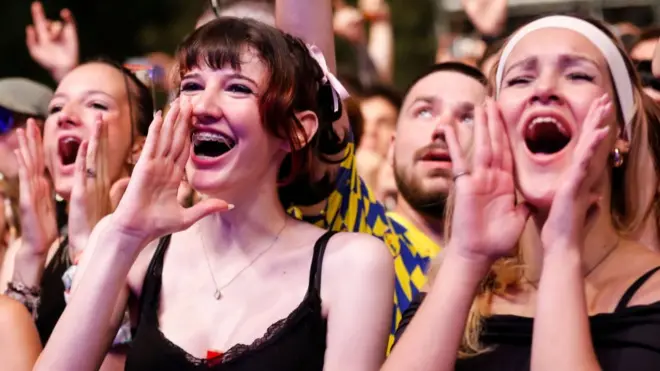 Women at Exit Festival hold their hands up to their mouths in Serbia in July 2024