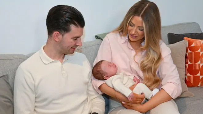 امرأة تحمل طفلاً رضيعاً وإلى جوارها رجل