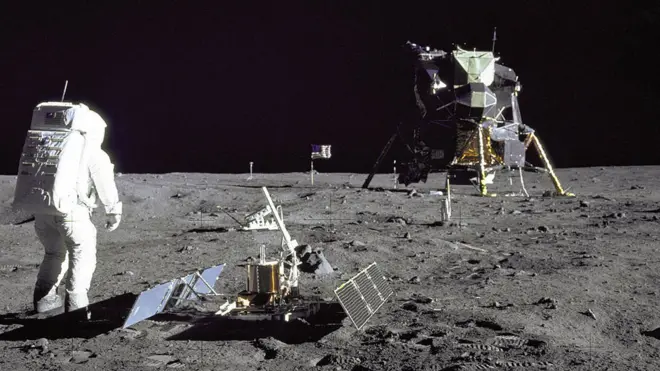 Aldrin despliega el experimento sísmico en la superficie lunar. Un poco más atrás se ve el experrimento del retroreflector y al fondo el módulo de alunizaje Águila.
