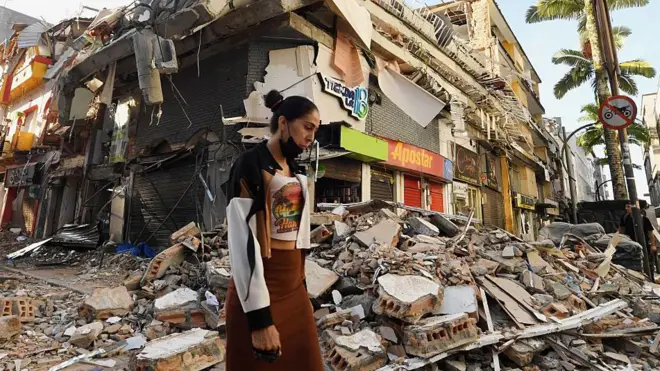 Mujer pasa antes casas destruidas en Pereira, Colombia