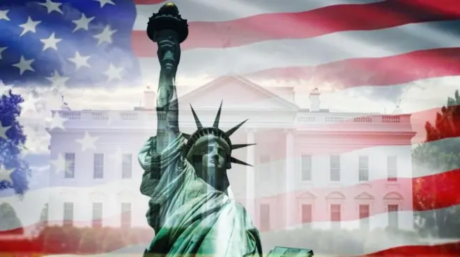 न्यूयोर्कस्थित स्ट्याचू अफ लिबर्टी, पृष्ठभूमिमा ह्वाइट हाउस र अमेरिकाको झण्डा