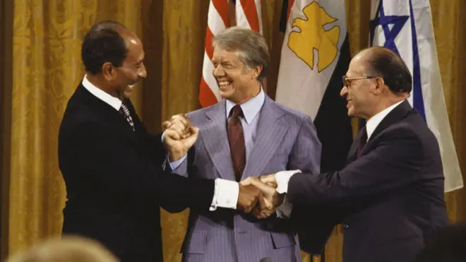 جیمی کارتر رئيس جمهور آمریکا در کنار انور سادات رئيس جمهور مصر و مناخیم بگین نخست وزیر اسرائيل در پی امضای پیمان کمپ دیوید