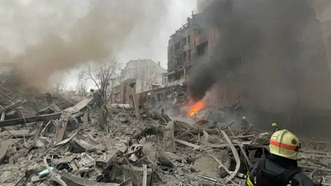 Зруйновані будинки, пожежа, видно рятувальника