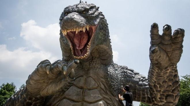 Crewmember Tetsuo Hayashi airbrushes the final touches to a 6.6 meter replica of the famous Godzilla at Tokyo Midtown on July 15, 2014 in Tokyo, Japan.