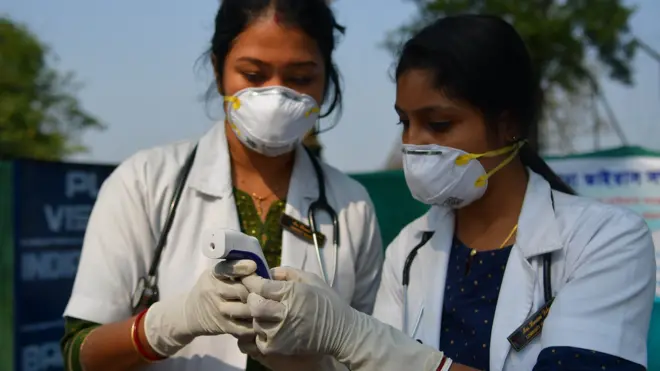 File photo showing two Indian doctors checking a thermometer