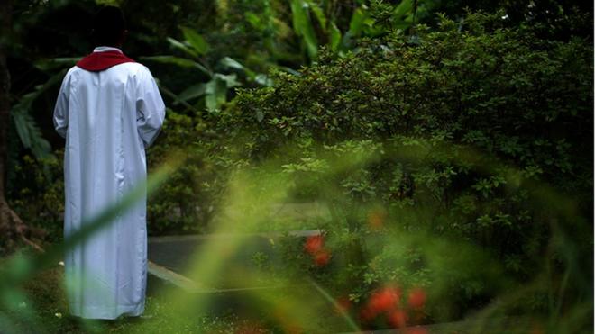 Un sacerdote de espaldas, vestido en alba blanca