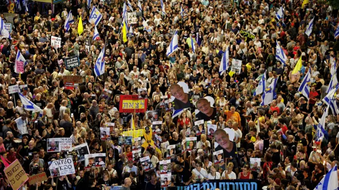 حشود من المتظاهرين في تل أبيب ليلاً يحملون يافطات وأعلام إسرائيل