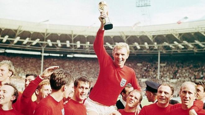 Bobby Moore, wearing red, holding the World Cup in 1966