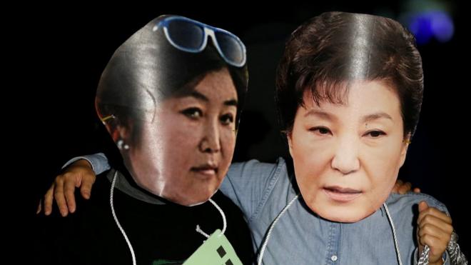 Protesters wearing masks of Choi Soon-sil (left) and President Park Geun-hye (centre) at a protest denouncing President Park in Seoul.