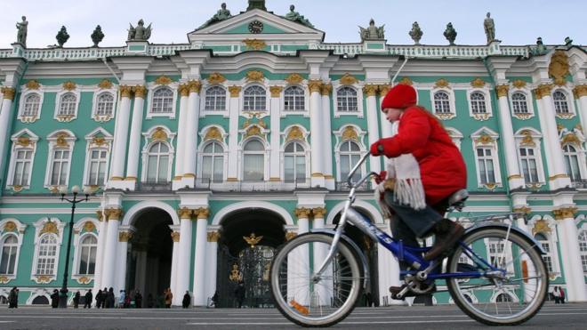 Девочка едет на велосипеде возле Зимнего дворца в Петербурге
