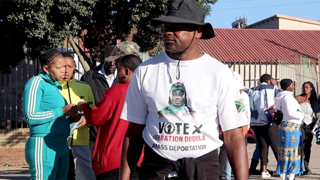 የኦፕሬሽን ዱዱላ ጽሁፍ ያለበት ነጭ ቲሸርት ያደረገ ወንድ