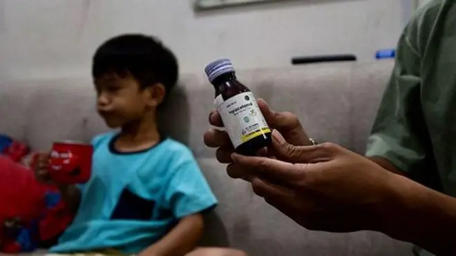 Riski Agri (kanan) menunjukkan sebotol sirup obat batuk yang dikonsumsi putranya Farrazka yang menyebabkan ginjalnya bermasalah.