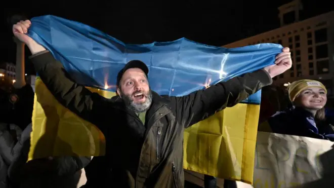 Seorang pria membentangkan bendera Ukraina di Lapangan Maidan, Kyiv, untuk merayakan pembebasan Kherson, pada 11 November 2022. 