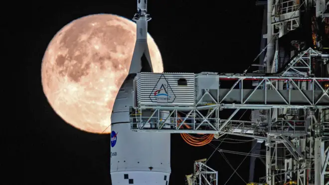 The Moon sets behind NASA's Artemis II SLS (Space Launch System) rocket and Orion spacecraft atop a mobile launcher at Launch Complex 39B at NASA's Kennedy Space Center in Florida on Sunday, February 1, 2026.