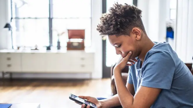 Umuhungu uri kureba kuri telephone ye