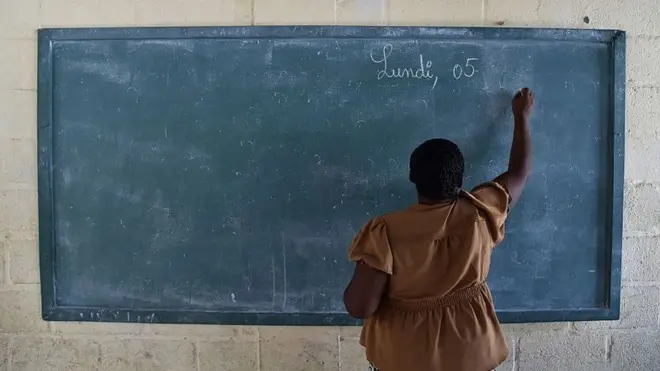 ጥቁር ሰሌዳ ላይ የምትጽፍ መምህር