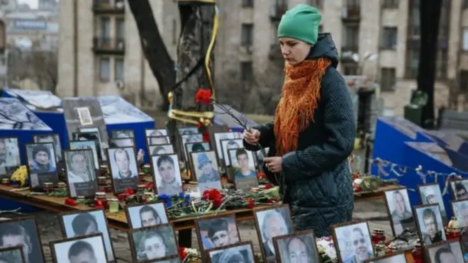 Дівчина з квітами біля фотографій загиблих