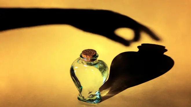 Aworan ojiji ọwọ kan to fẹ mu igo